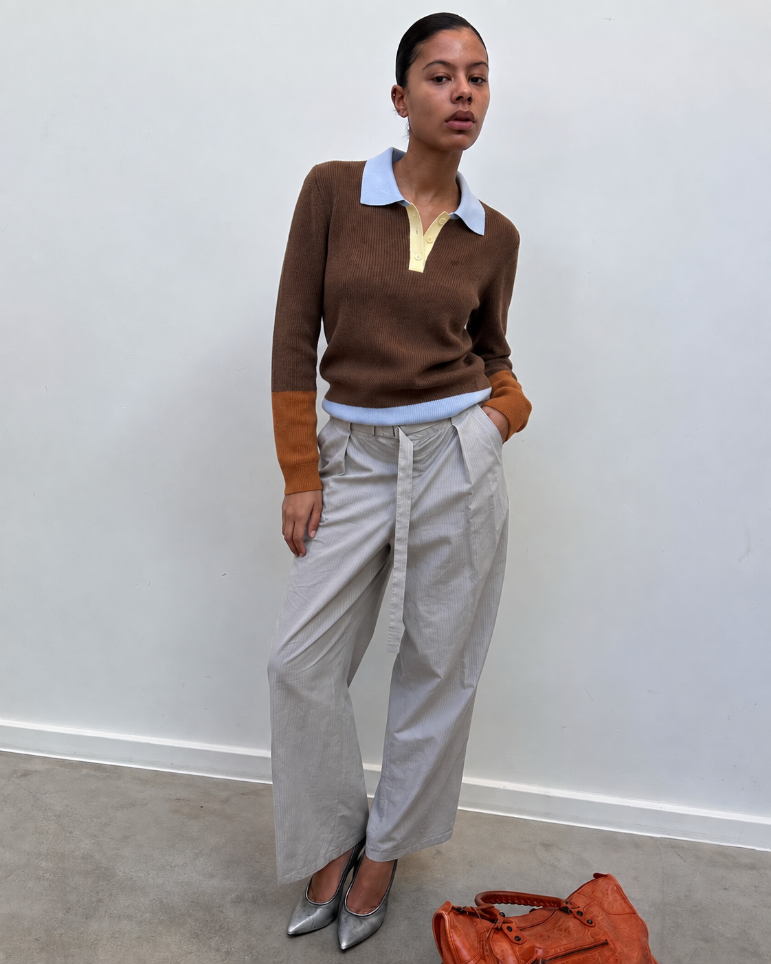Pull col polo chocolat porté avec un pantalon gris