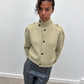 Cardigan boutonné à col montant vert pâle porté avec un pantalon gris
