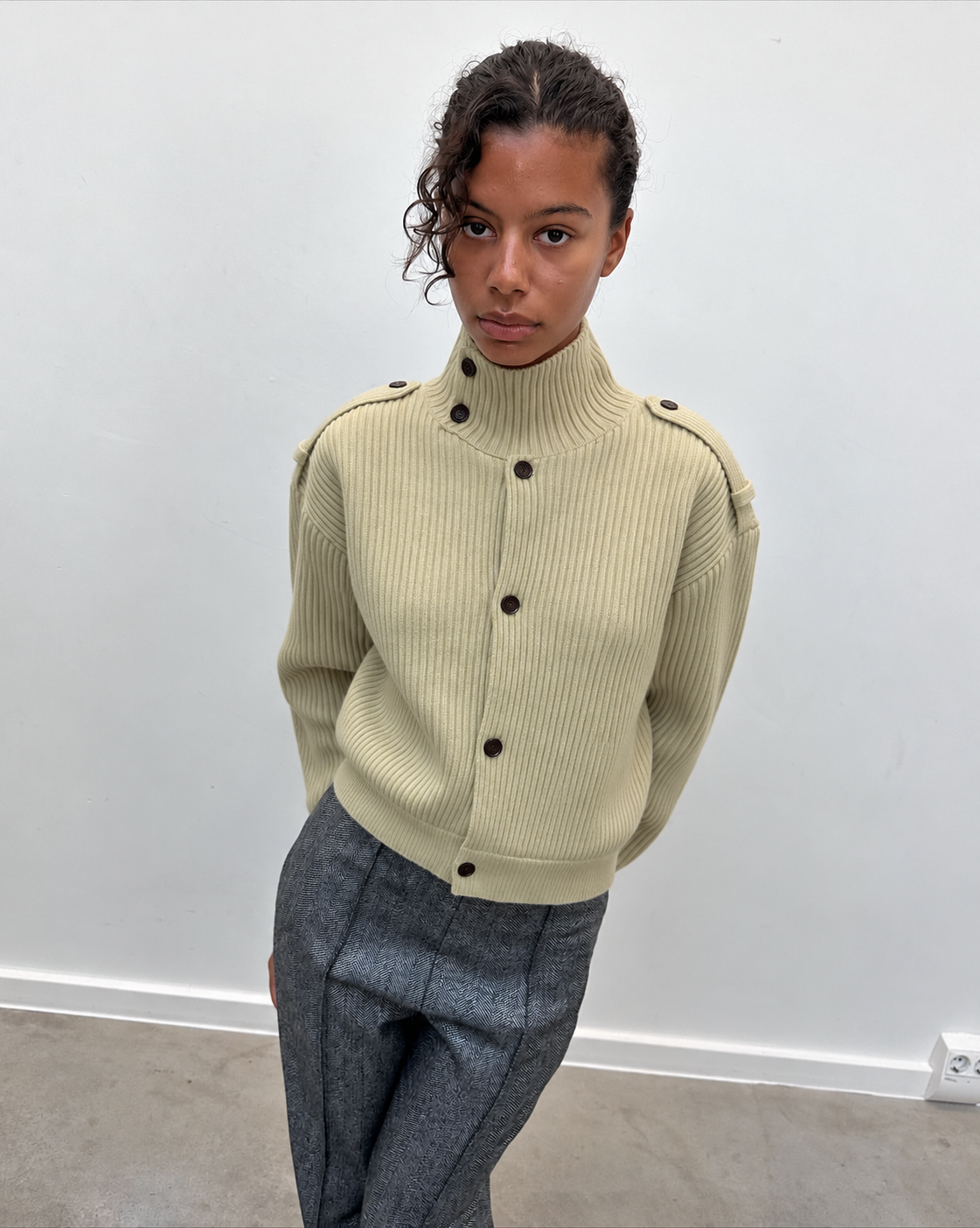 Cardigan boutonné à col montant vert pâle porté avec un pantalon gris