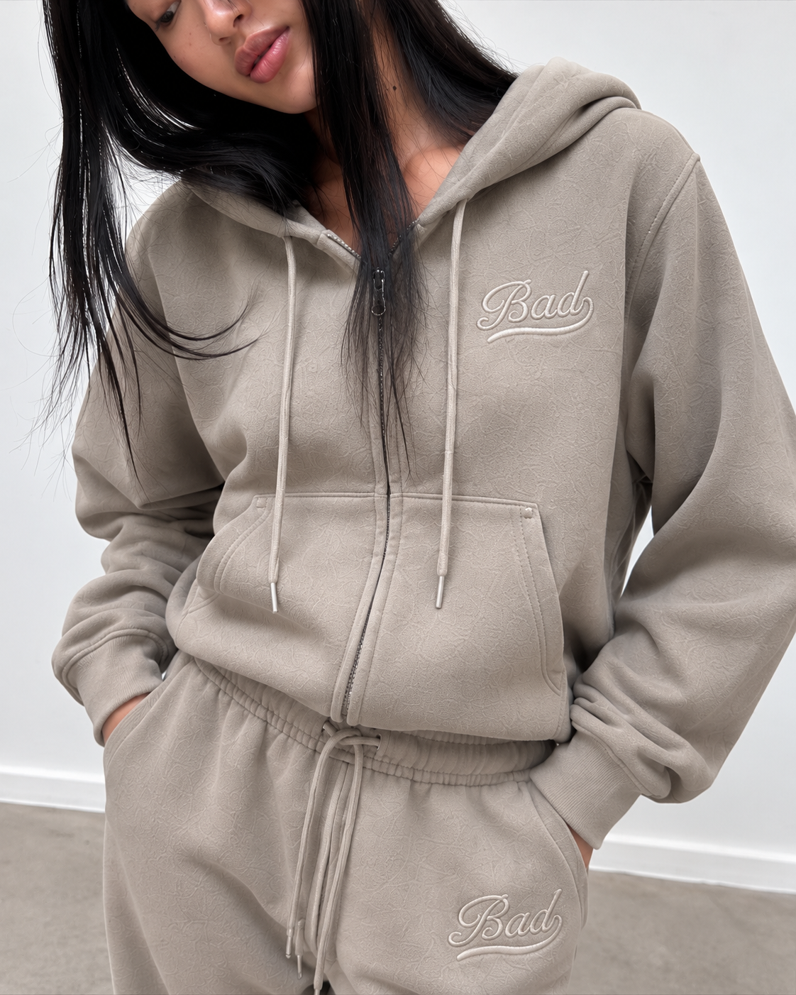 Détail de la broderie ton sur ton du gilet zippé et du jogging taupe