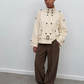 Trench court écru porté avec un pantalon large marron