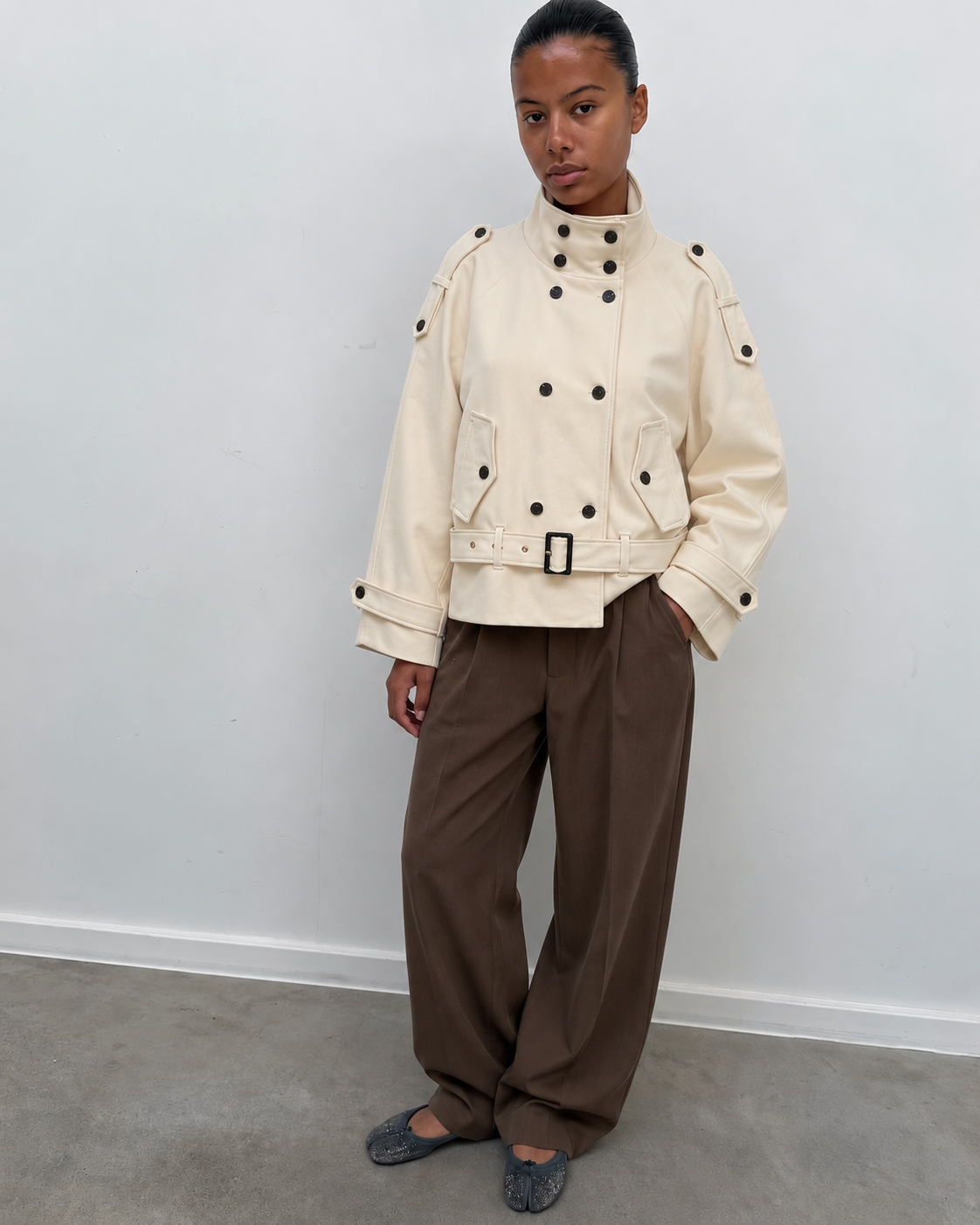 Trench court écru porté avec un pantalon large marron