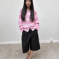 Chemise en maille rose pâle portée avec un short noir