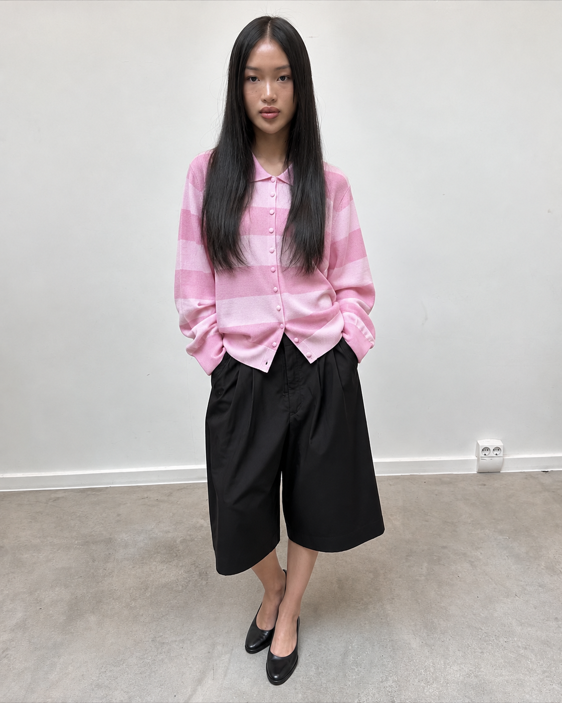 Chemise en maille rose pâle portée avec un short noir